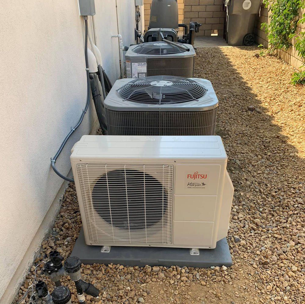 A row of air conditioners are sitting outside of a building.