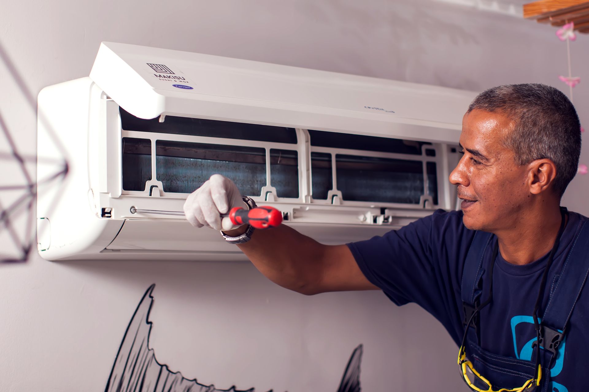 Man repairing a wall-mounted AC unit, providing expert AC repair for reliable cooling.