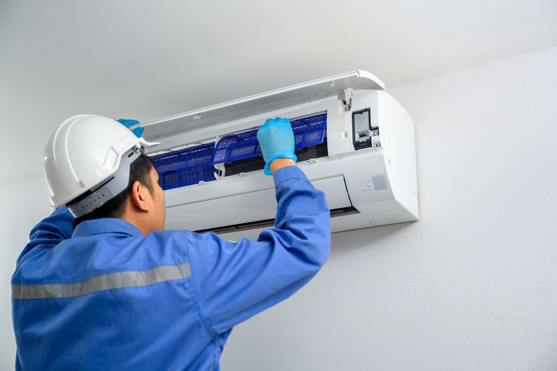 Male AC technician installing an air conditioner in a home.
