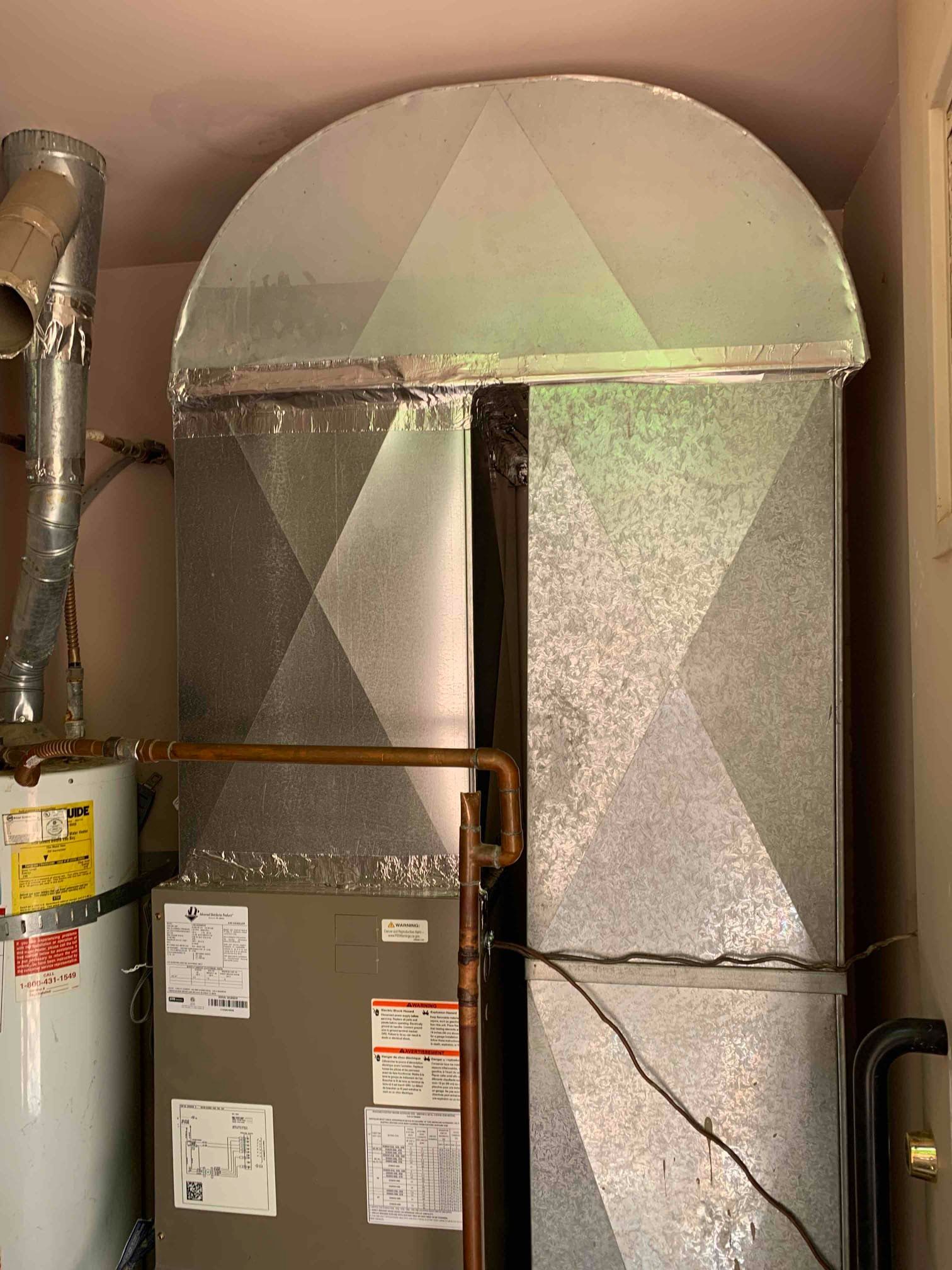 A furnace and water heater are in a utility closet with ductwork overhead.