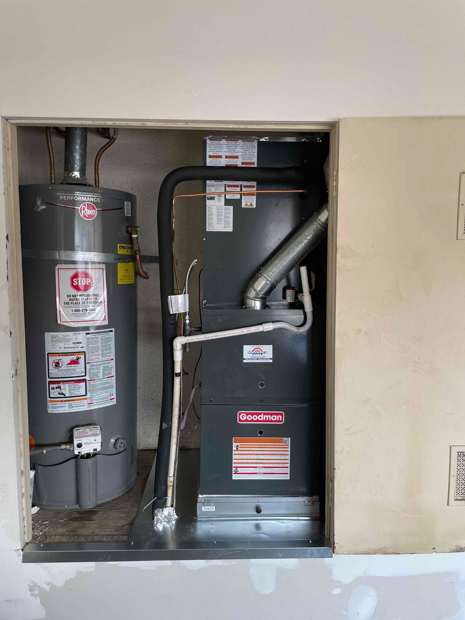 Water heater and HVAC system enclosed in a utility closet with metal and grey components.