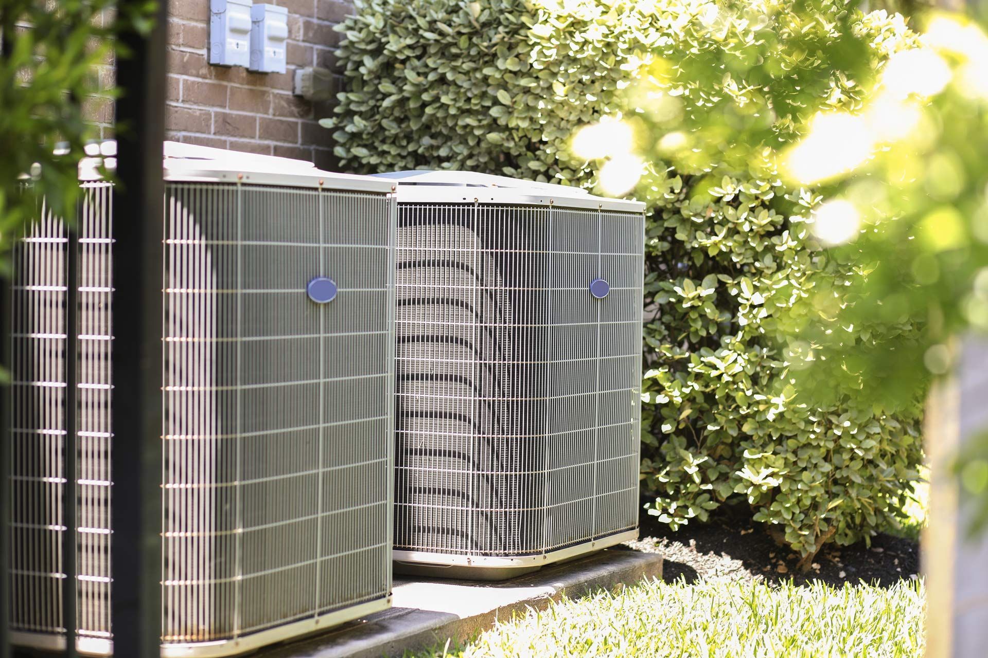 Three air conditioners are sitting outside of a brick building.