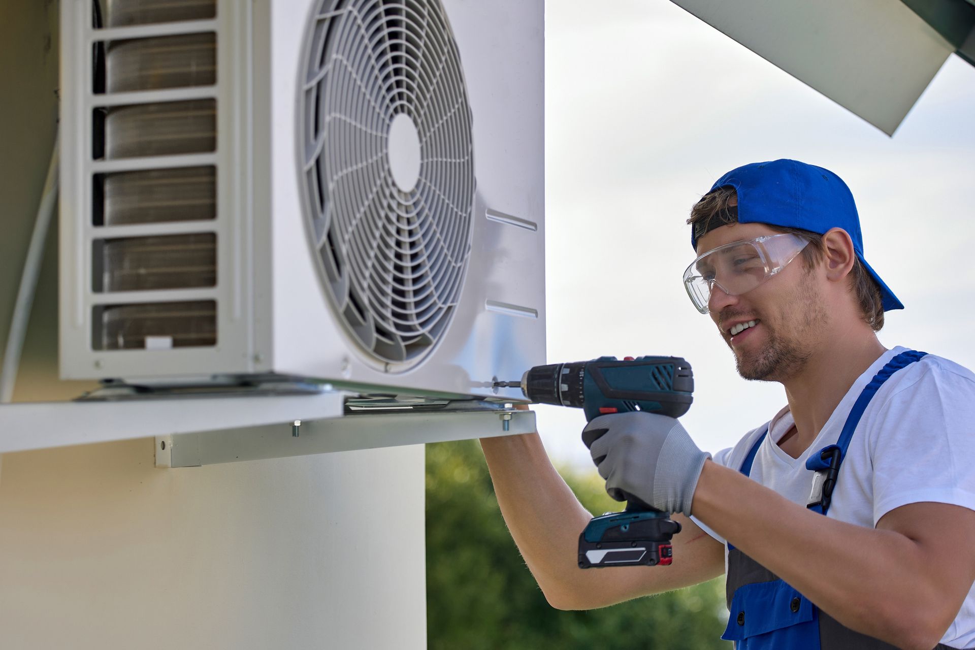 A worker installs the outer metal case of the air conditioner with a screwdriver. A worker installs the outer metal case of the air conditioner with a screwdriver.