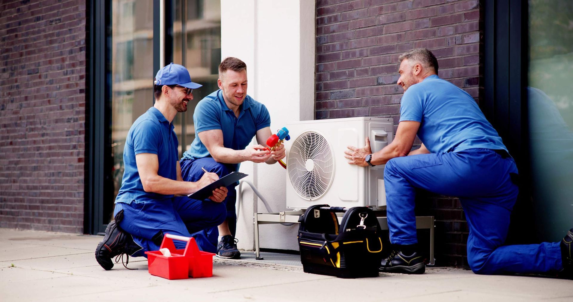 A gray air conditioner is sitting on a concrete floor next to a wall.