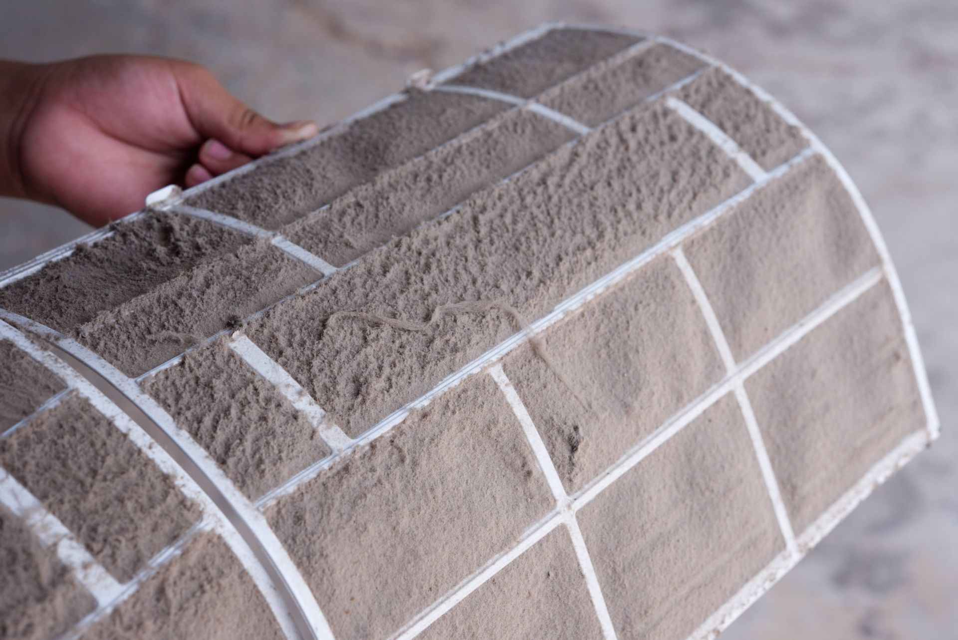 A person is holding a dirty air filter in their hand.