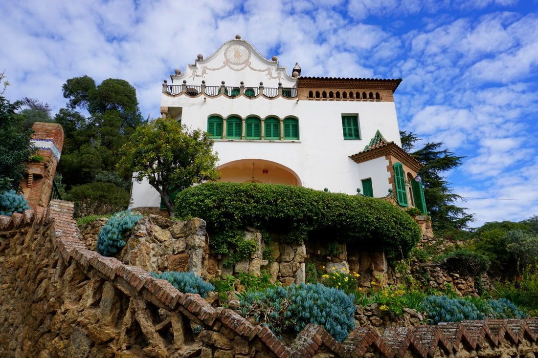 A large white house with green windows sits on top of a hill