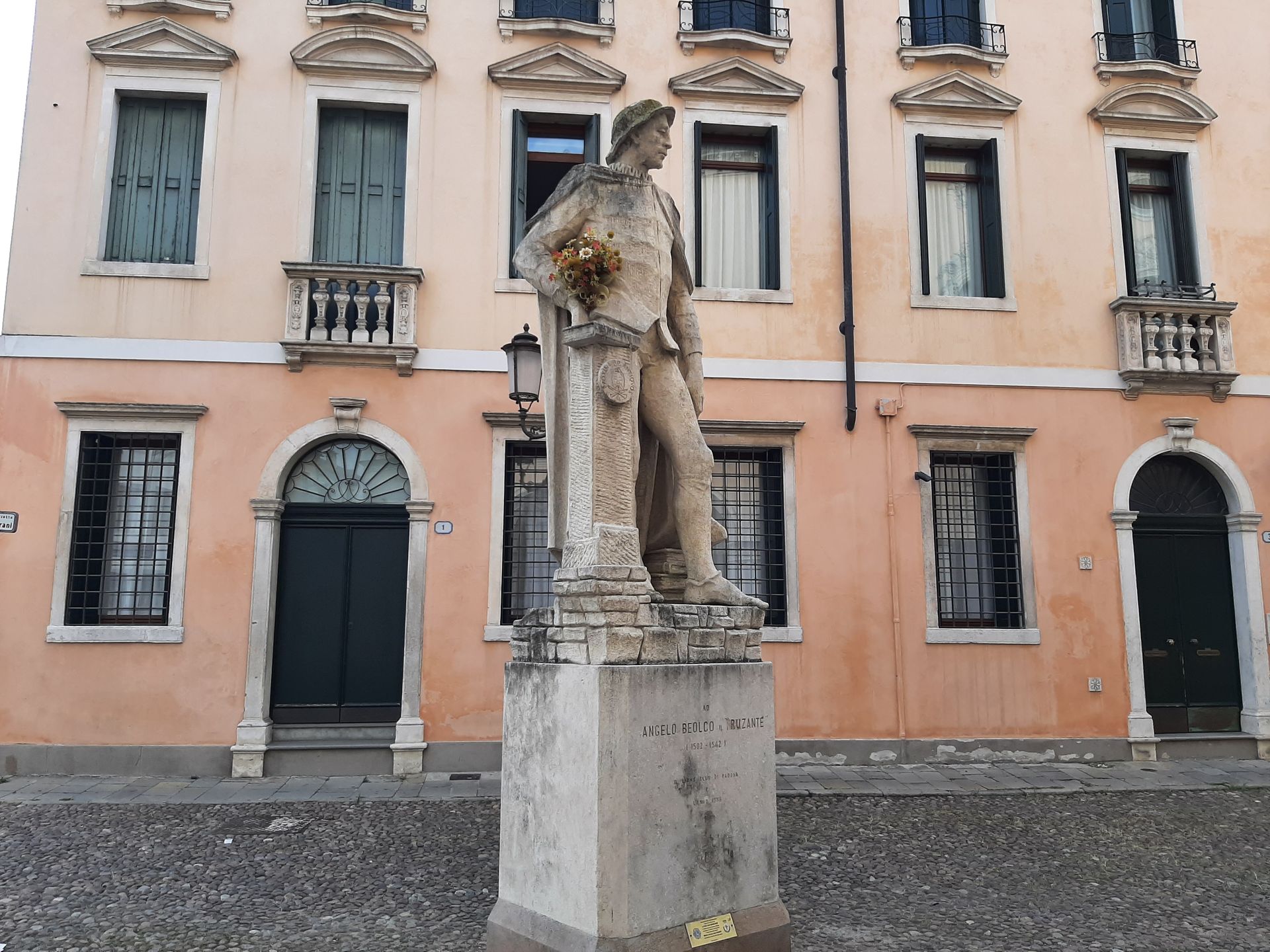 A statue of a man holding a bouquet of flowers in front of a building