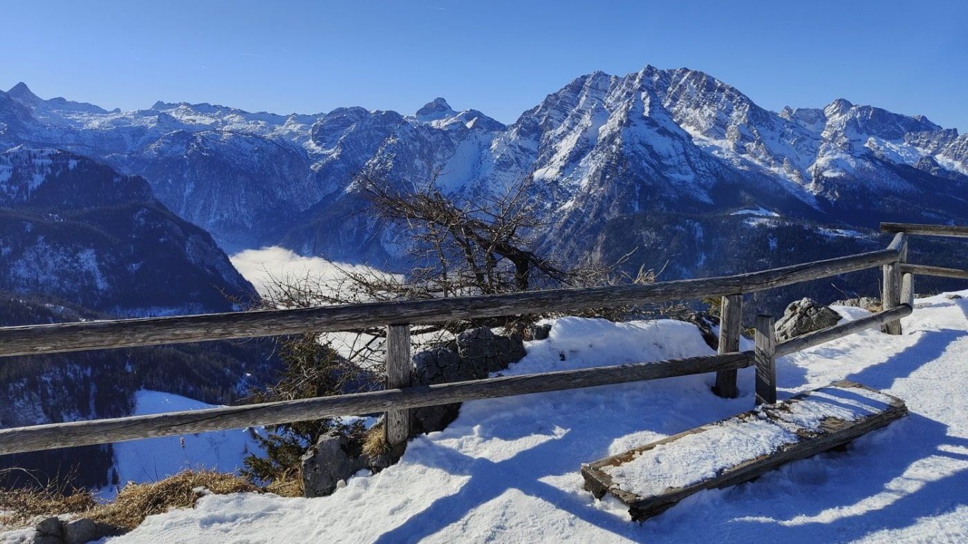 A snowy mountain range with a wooden fence in the foreground