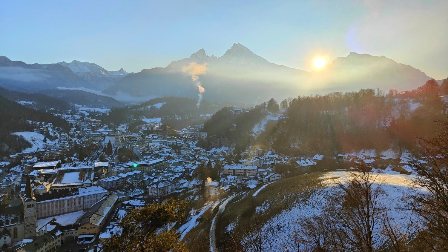 The sun is shining through the clouds over the mountains