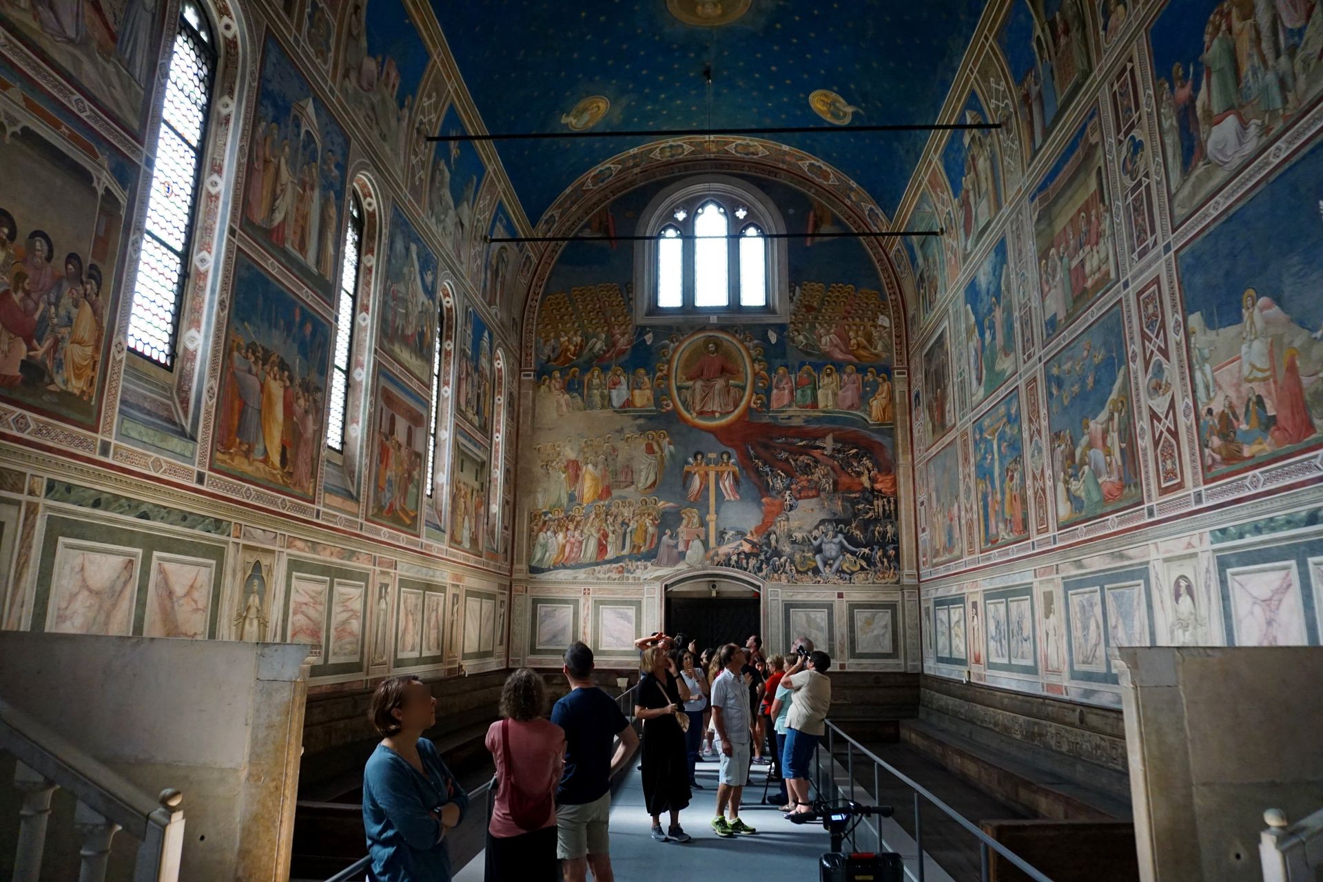 A group of people standing inside of a building with paintings on the walls