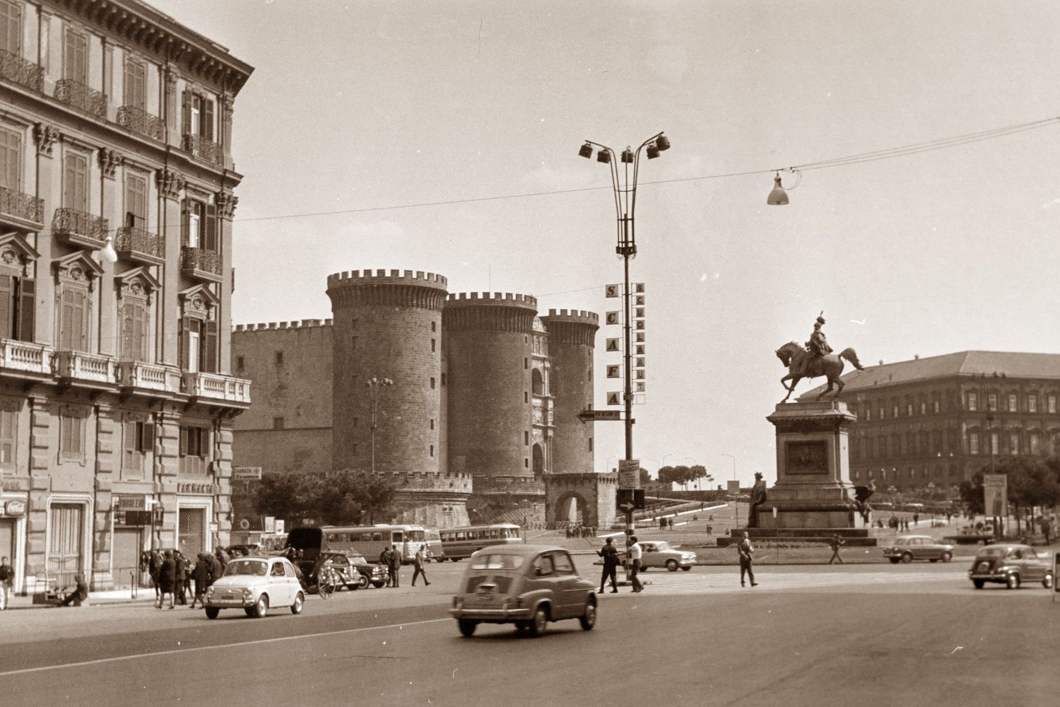 A black and white photo of a city street with a statue in the background