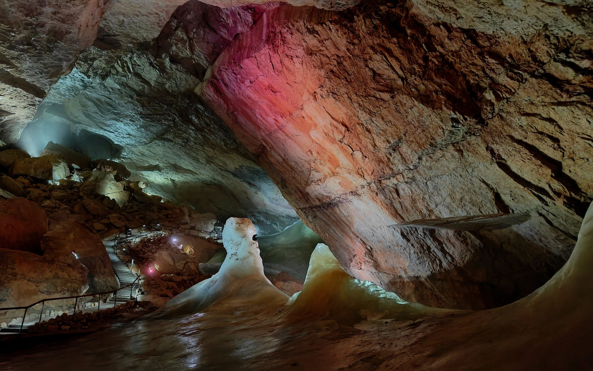 Rieseneishöhle Dachstein Krippenstein Cave interior with colorful lighting illuminating rock formations and icy stalagmites.