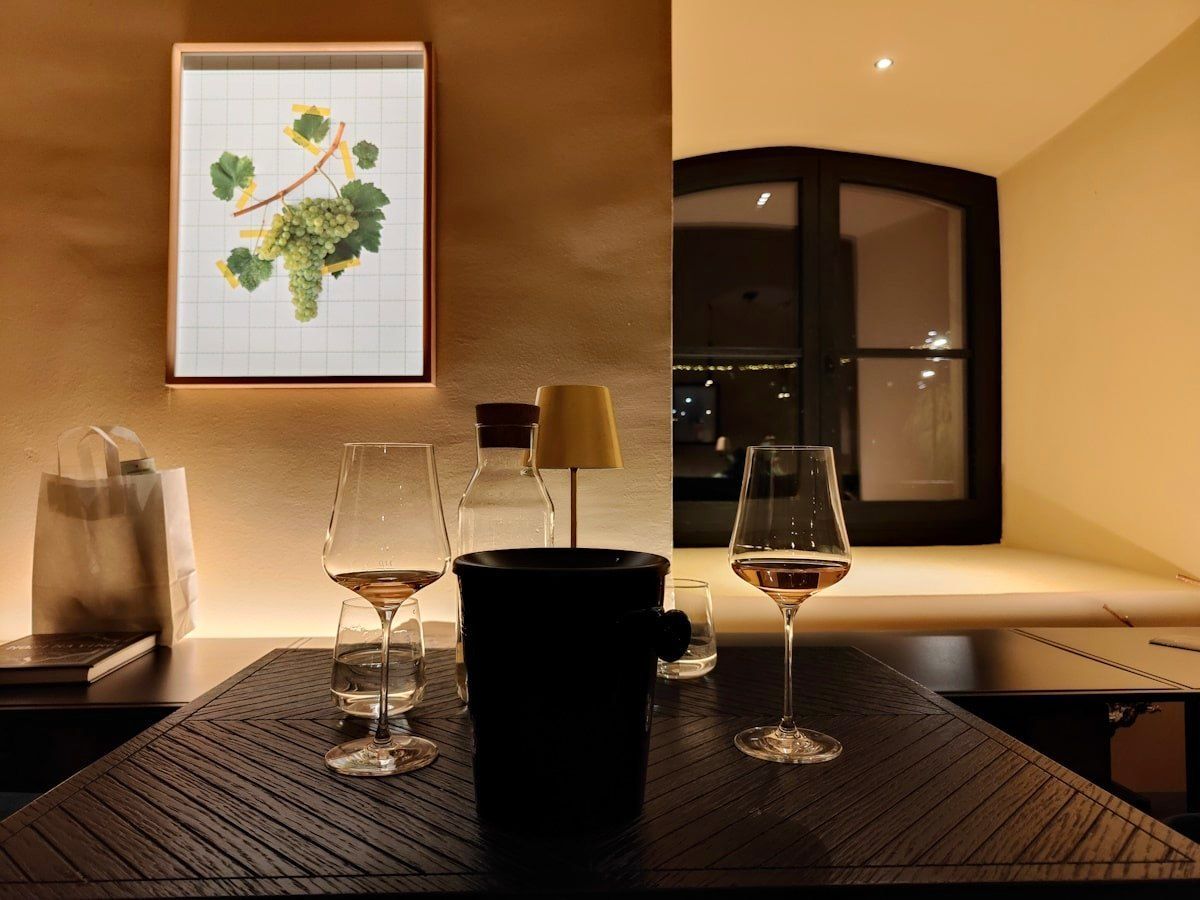 Maribor Weinverkostung Wine glasses on a table set for tasting. A grape illustration hangs on the wall.