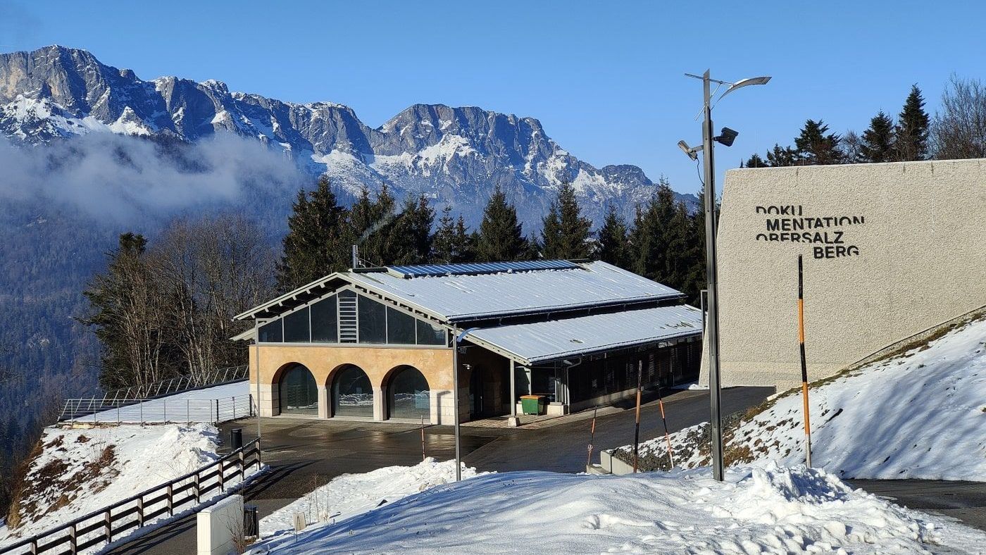 A snowy landscape with a building in the foreground and mountains in the background