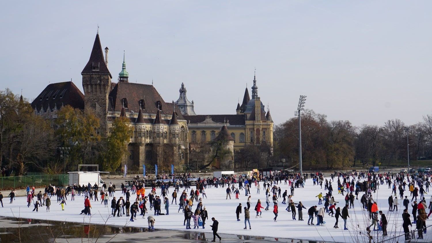 A large group of people are ice skating in front of a large building