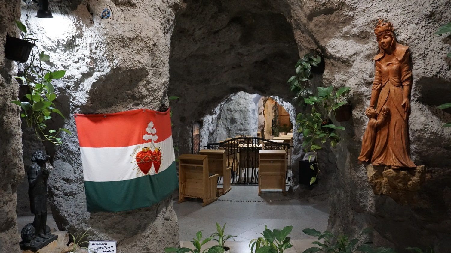 A cave with a flag and a statue in it (Budapest Felsenkirche)