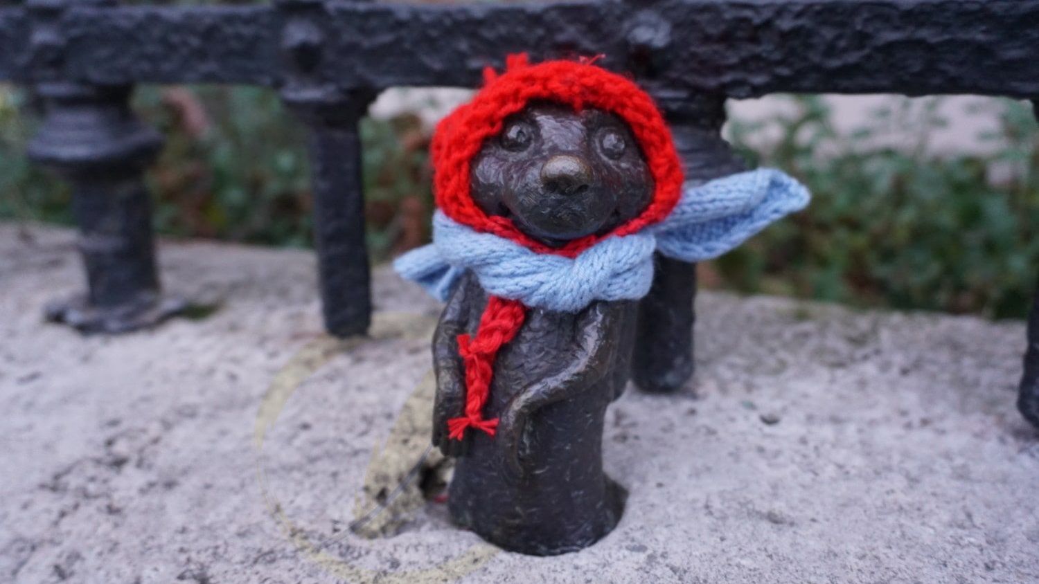 A statue of a bear wearing a red hat and scarf