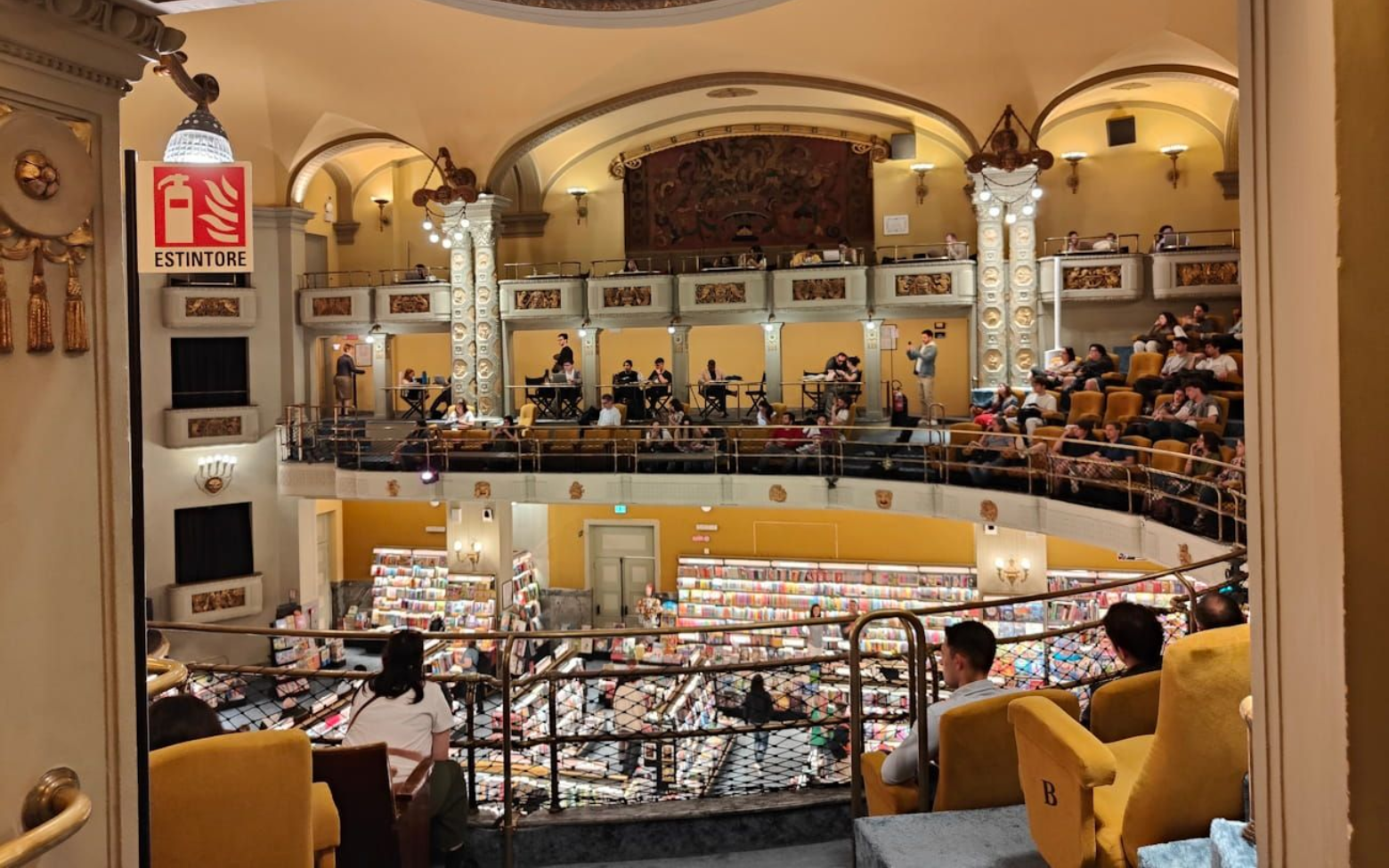 A bookstore, with shelves of books visible from the balcony seating of an ornate, historic hall.
