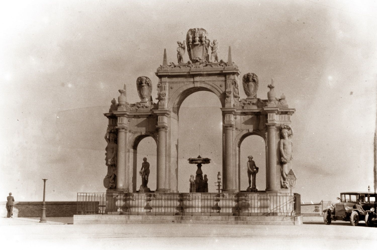 A black and white photo of a monument with a car parked in front of it