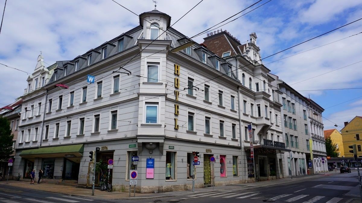 A large white building is on the corner of a street