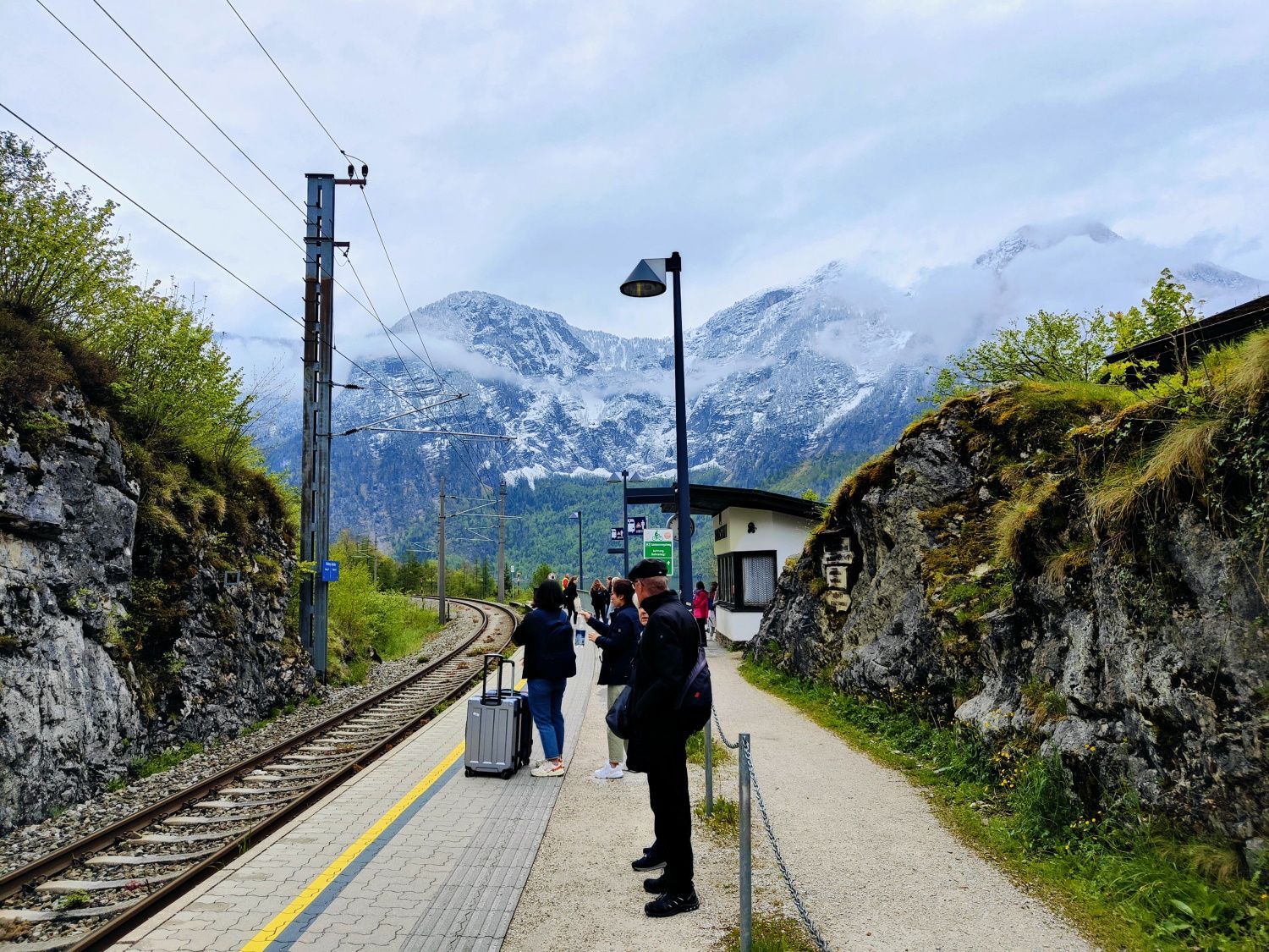 People waiting for a train with mountains in the background