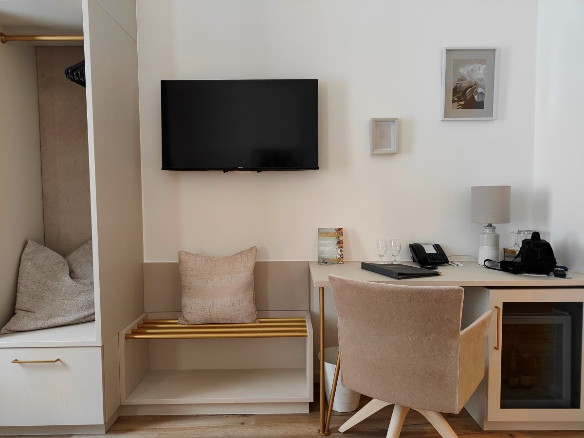 A room with a desk chair and a flat screen tv