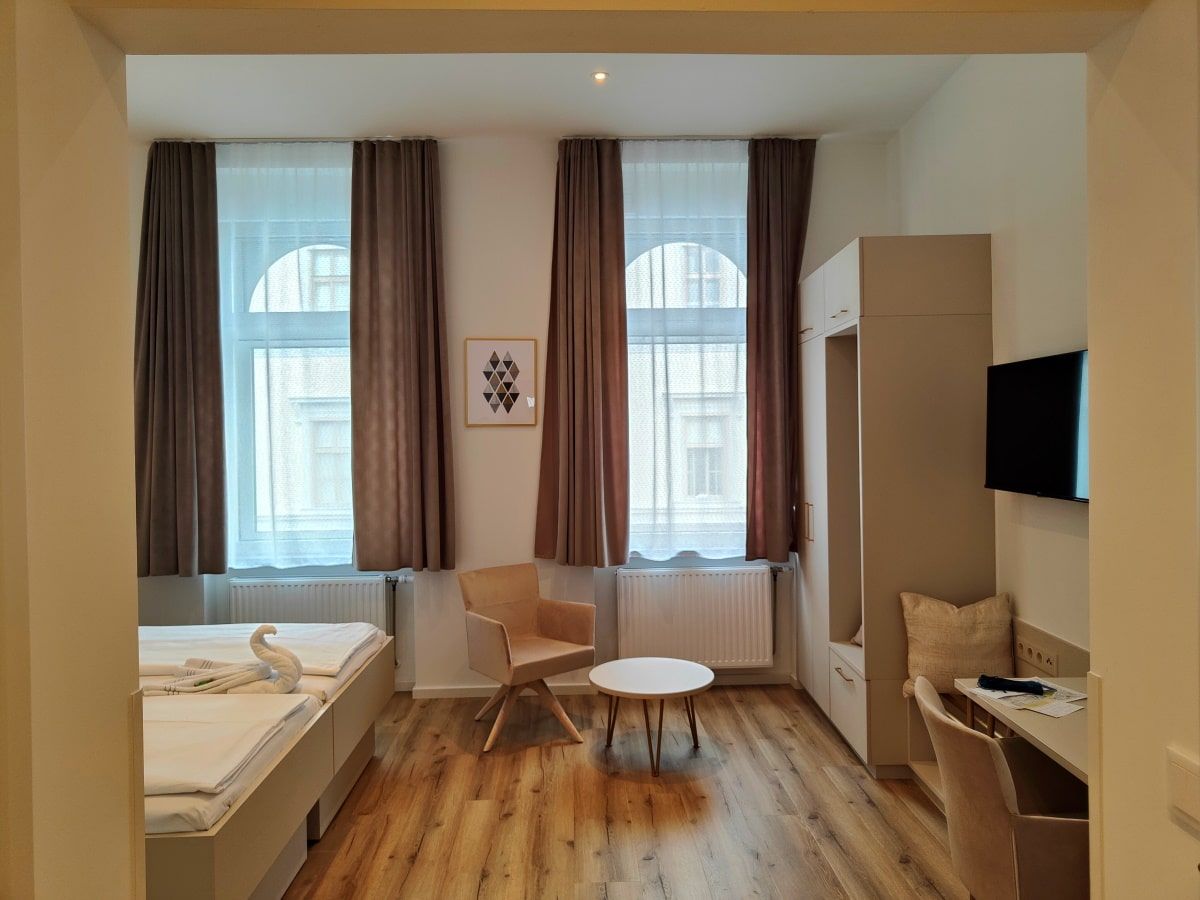 A bedroom with two beds a chair and a table