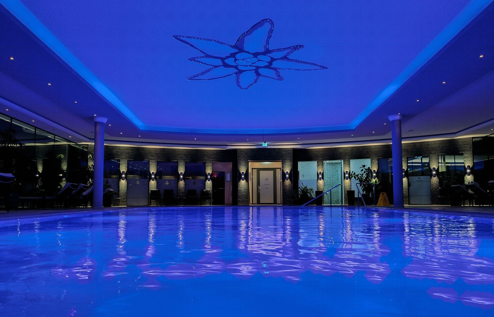 A large indoor swimming pool is lit up with blue lights