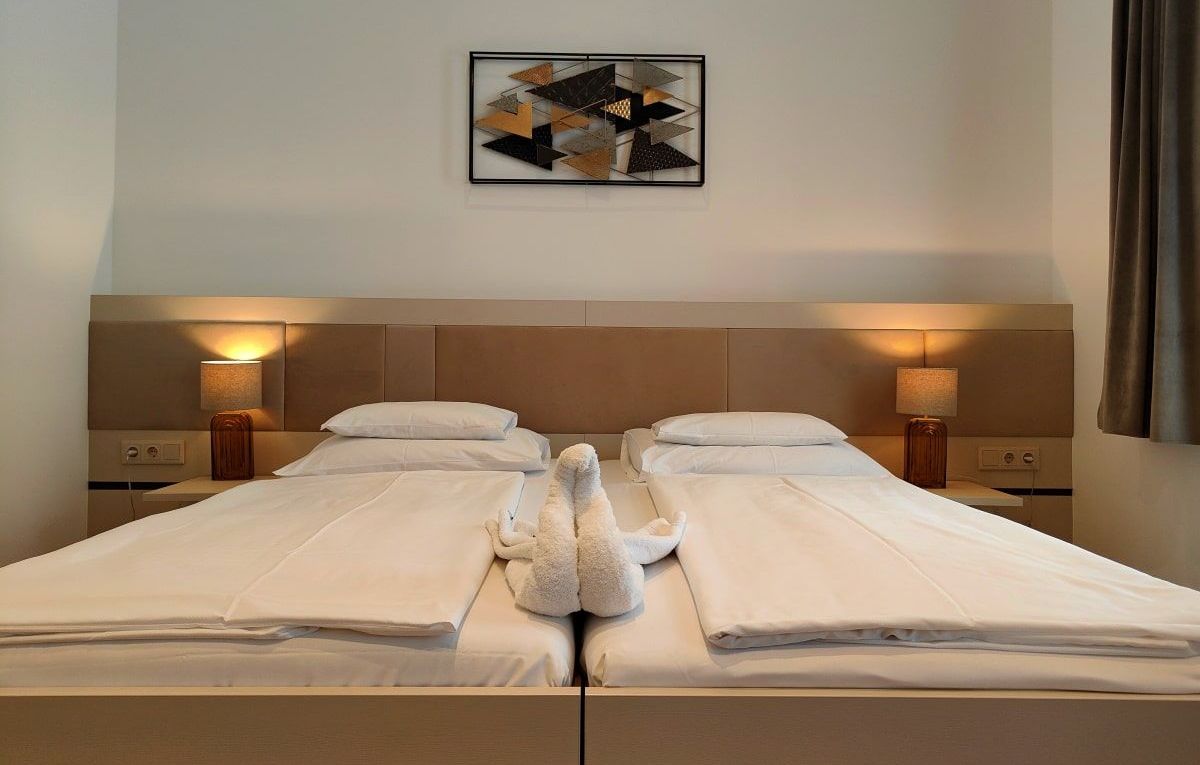 A hotel room with two beds and a painting on the wall
