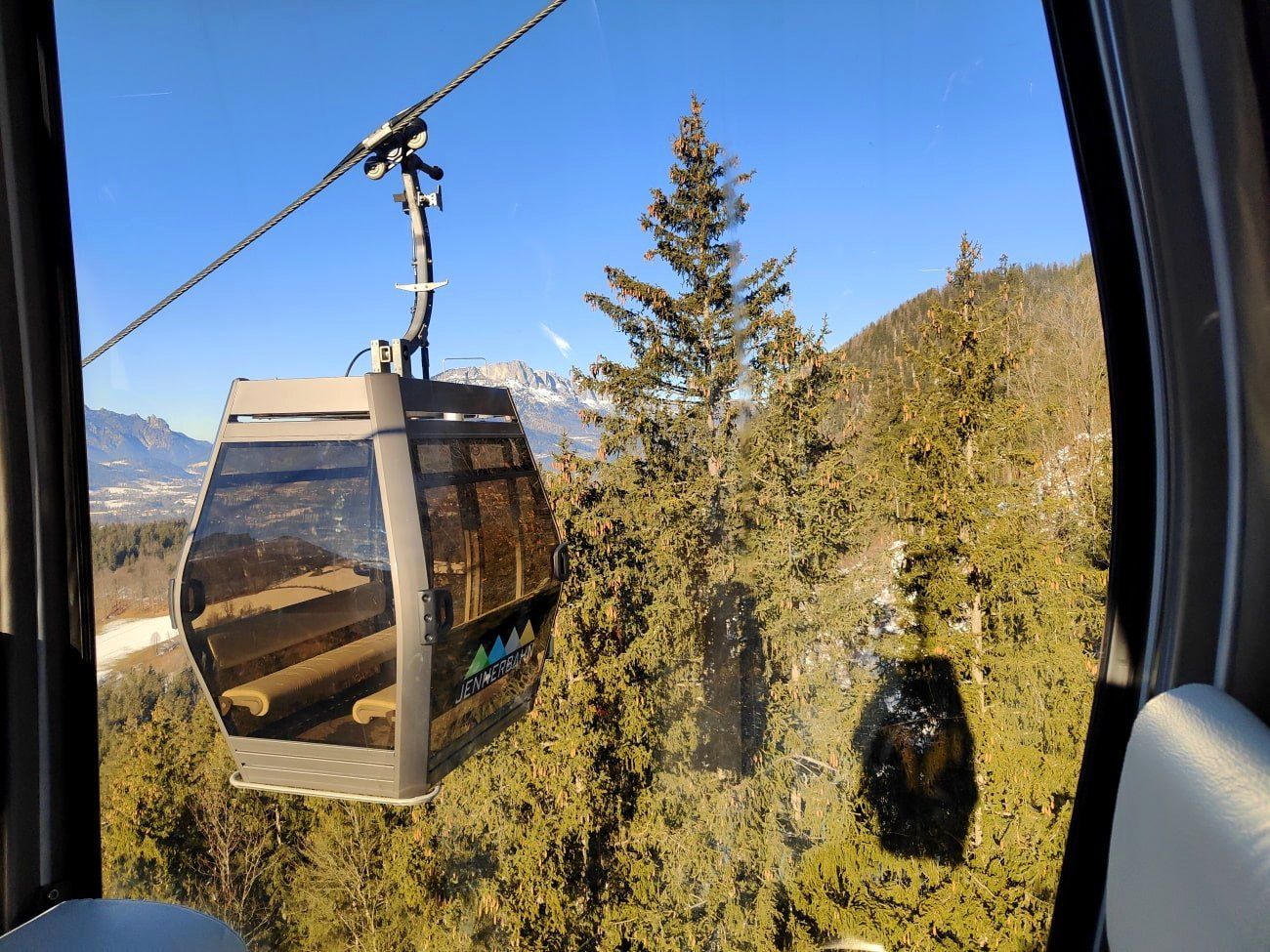 A cable car going up a mountain with trees in the background