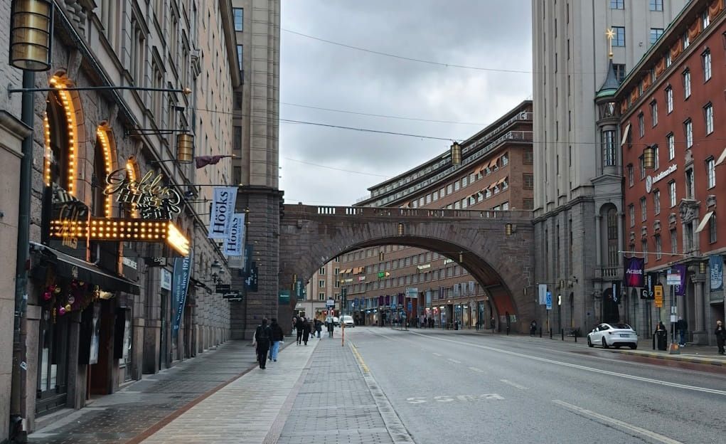 Empty cobblestone street with a large stone arch bridge between buildings on an overcast city morning