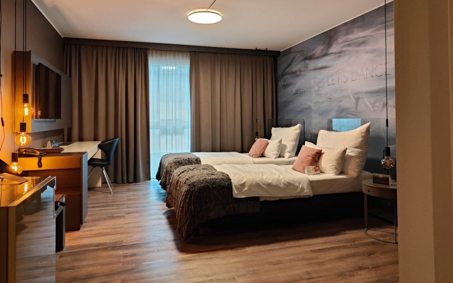 Maribor City Hotel Hotel room with two twin beds, desk, and large window with tan curtains.