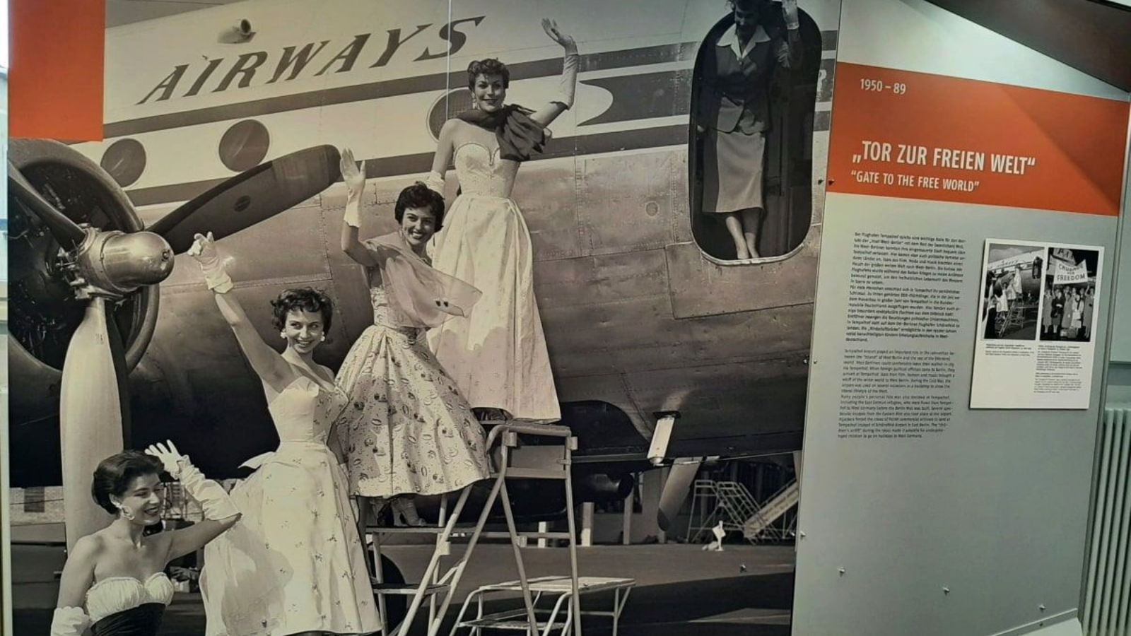Mythos Tempelhof Berlin Women in gowns pose on stairs near a vintage airplane labeled
