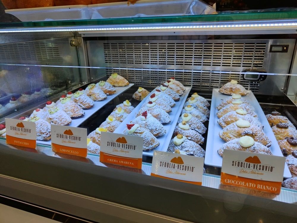 A variety of pastries are displayed in a glass case