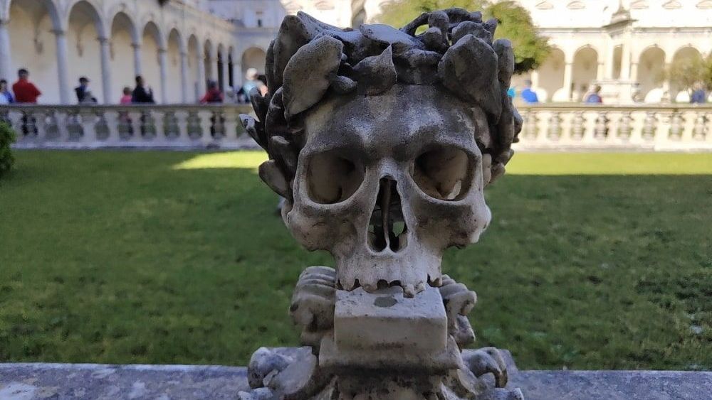 A statue of a skull with a laurel wreath on it