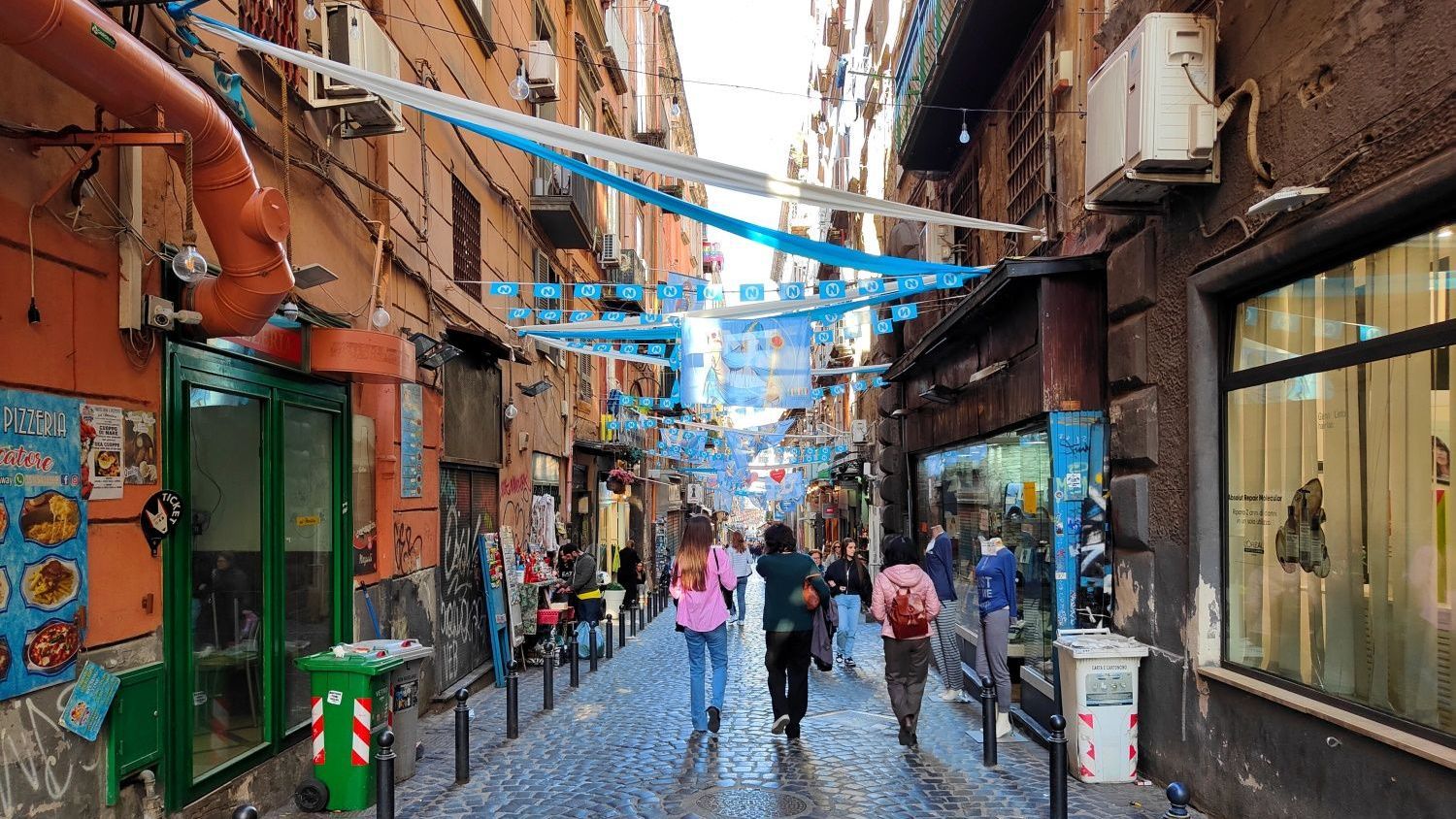 People walking down a cobblestone street in Napoli