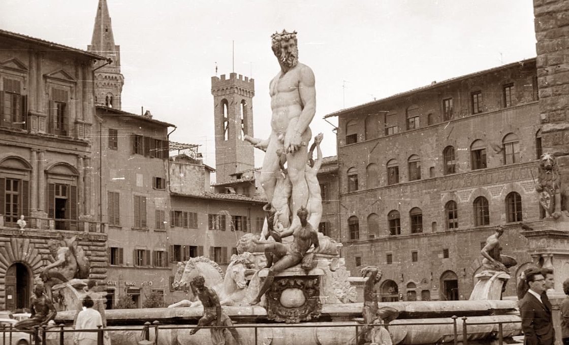 A sepia-toned shot of the Neptune Fountain in Florence's Piazza della Signoria with surrounding historic architecture.