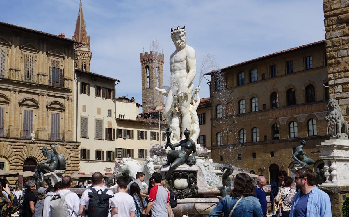 The central courtyard of the Bargello Museum in Florence, featuring stone pillars, painted arches, and a central fountain.