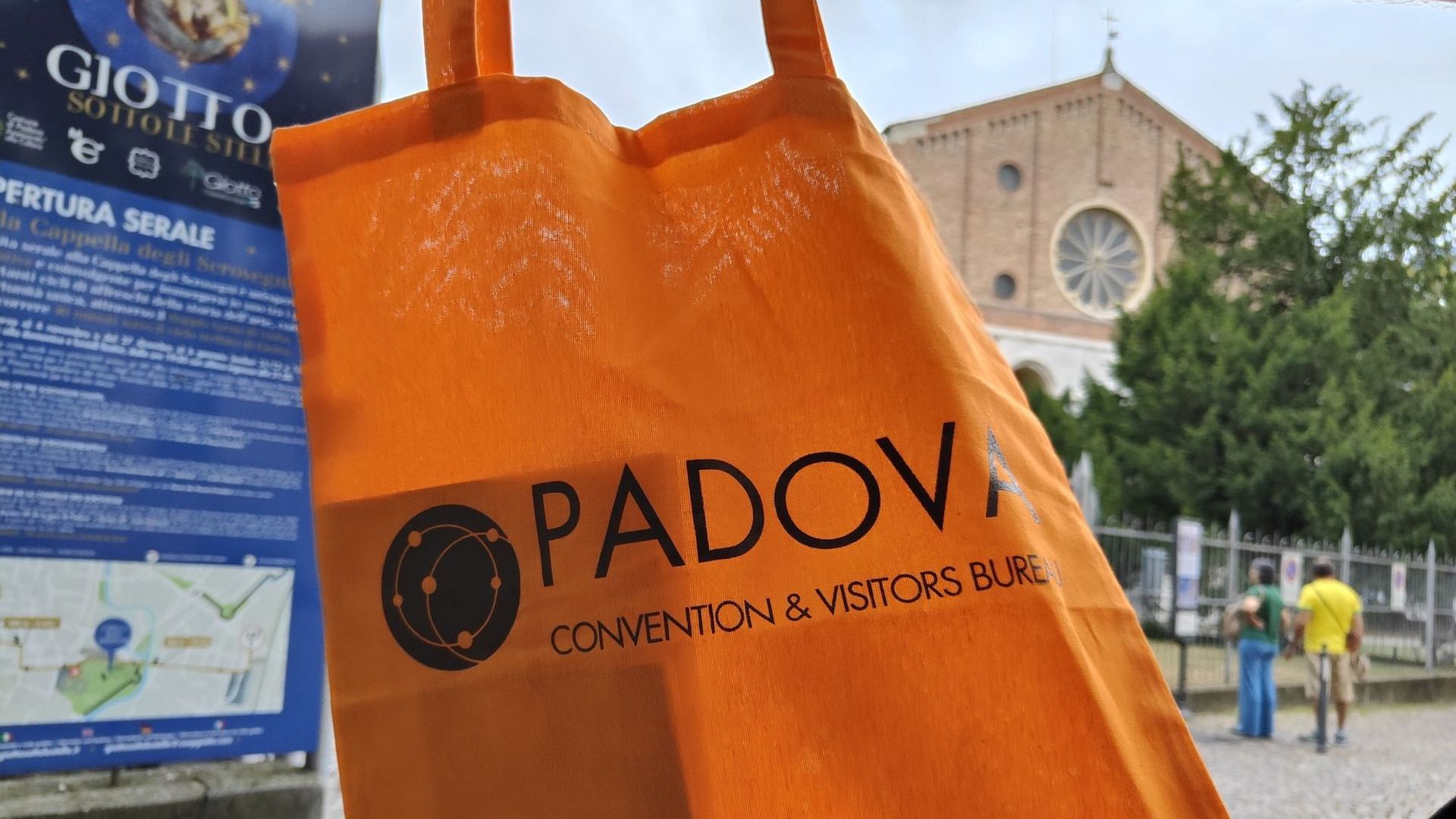 A person is holding an orange bag that says padova