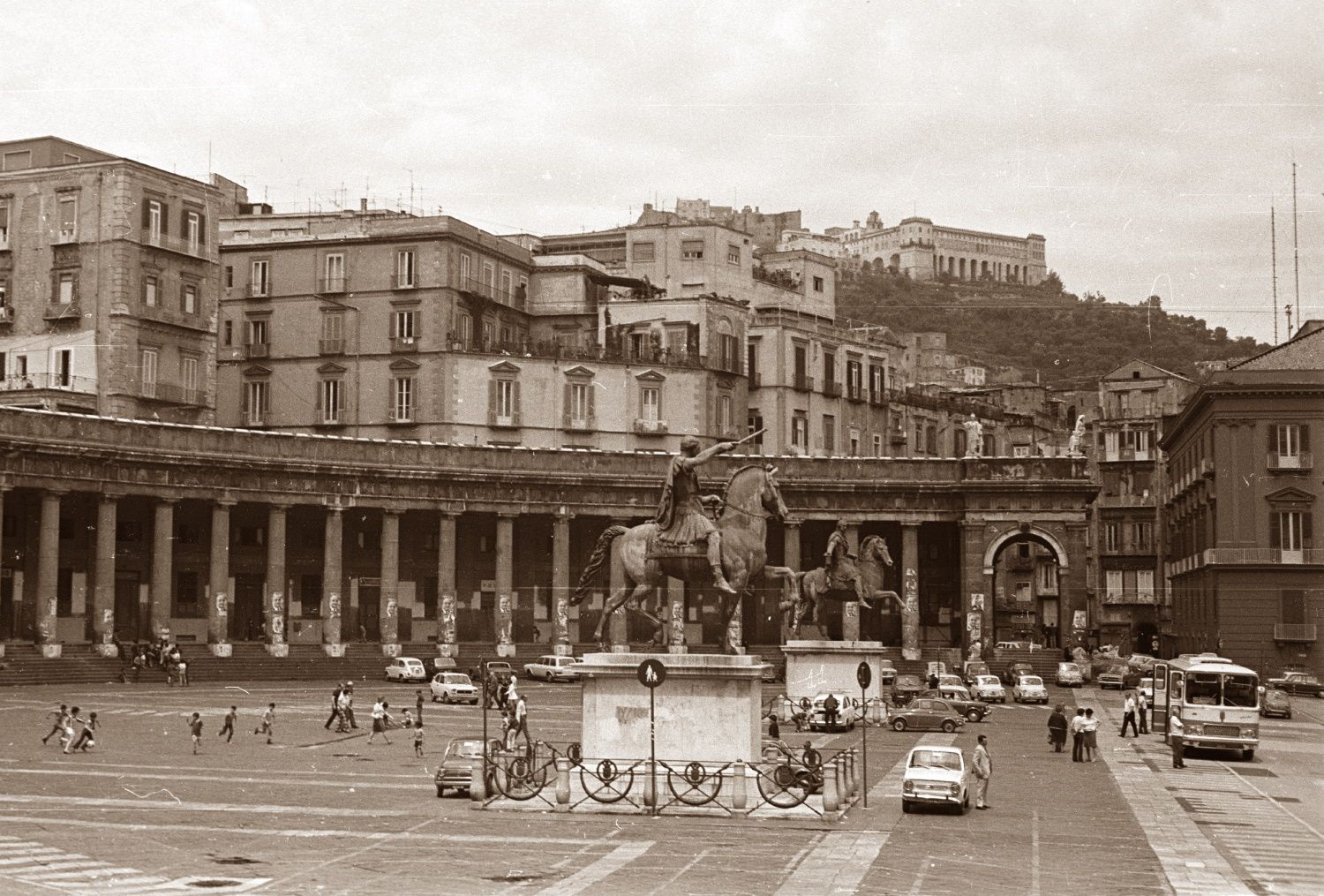 A black and white photo of a city with a statue in the middle