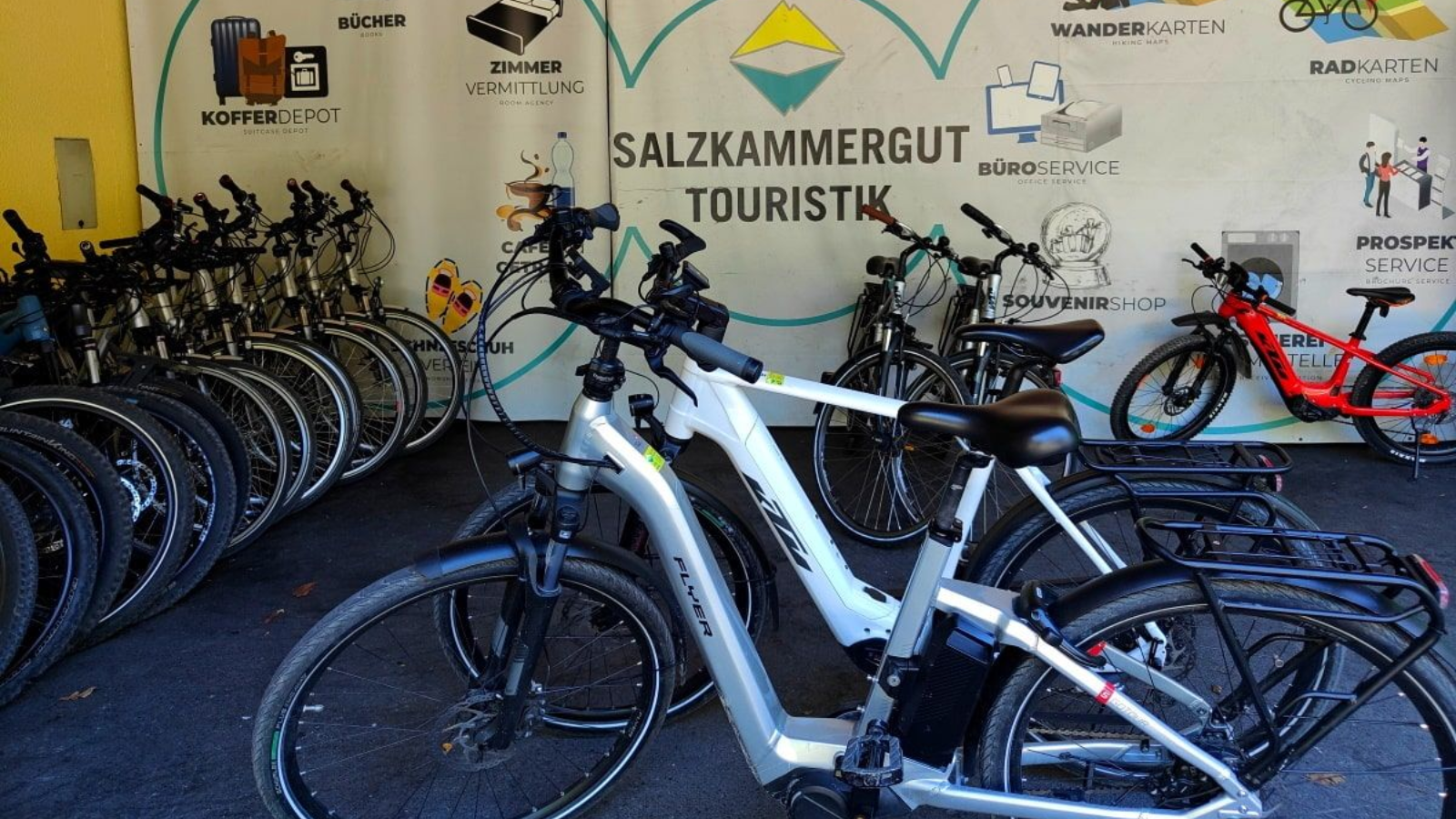 Bikes parked in a rack at a tourism site with a sign for Salzkammergut Touristik.