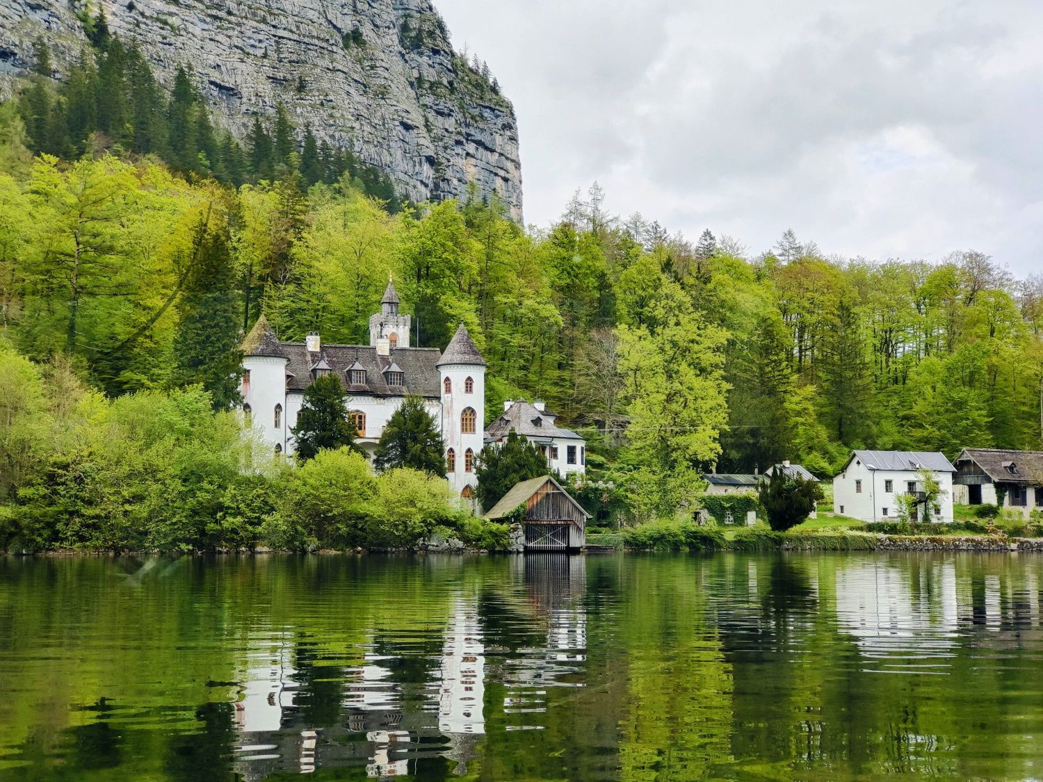 A castle sits on the shore of a lake surrounded by trees