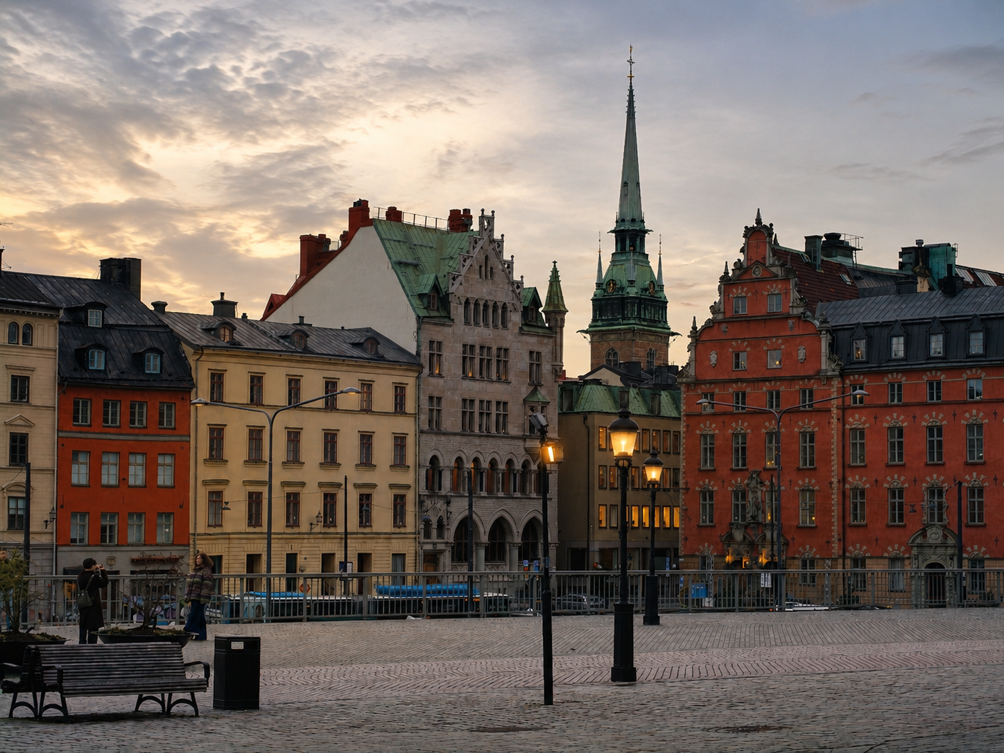 Stockholmer Platz mit farbenfrohen Gebäuden und einem hohen Kirchturm im Sonnenuntergang.