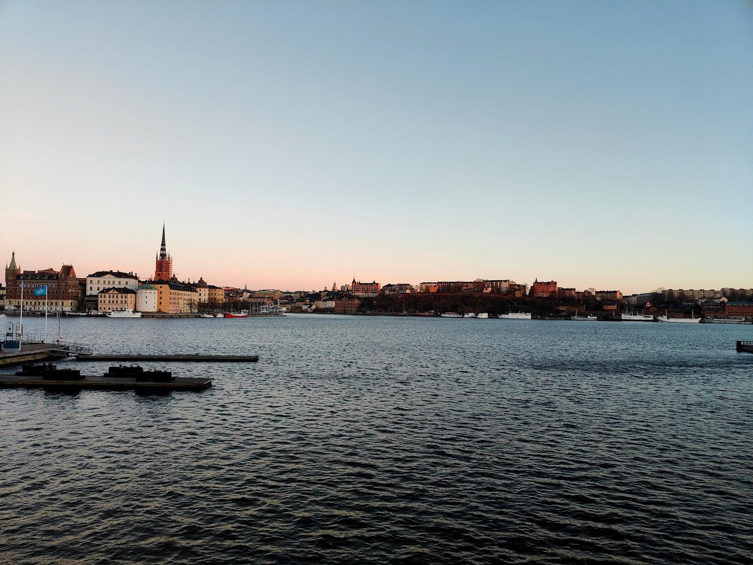 Ruhige Skyline der Stadt am Wasser bei Sonnenuntergang mit Brücke und sanft plätscherndem Wasser