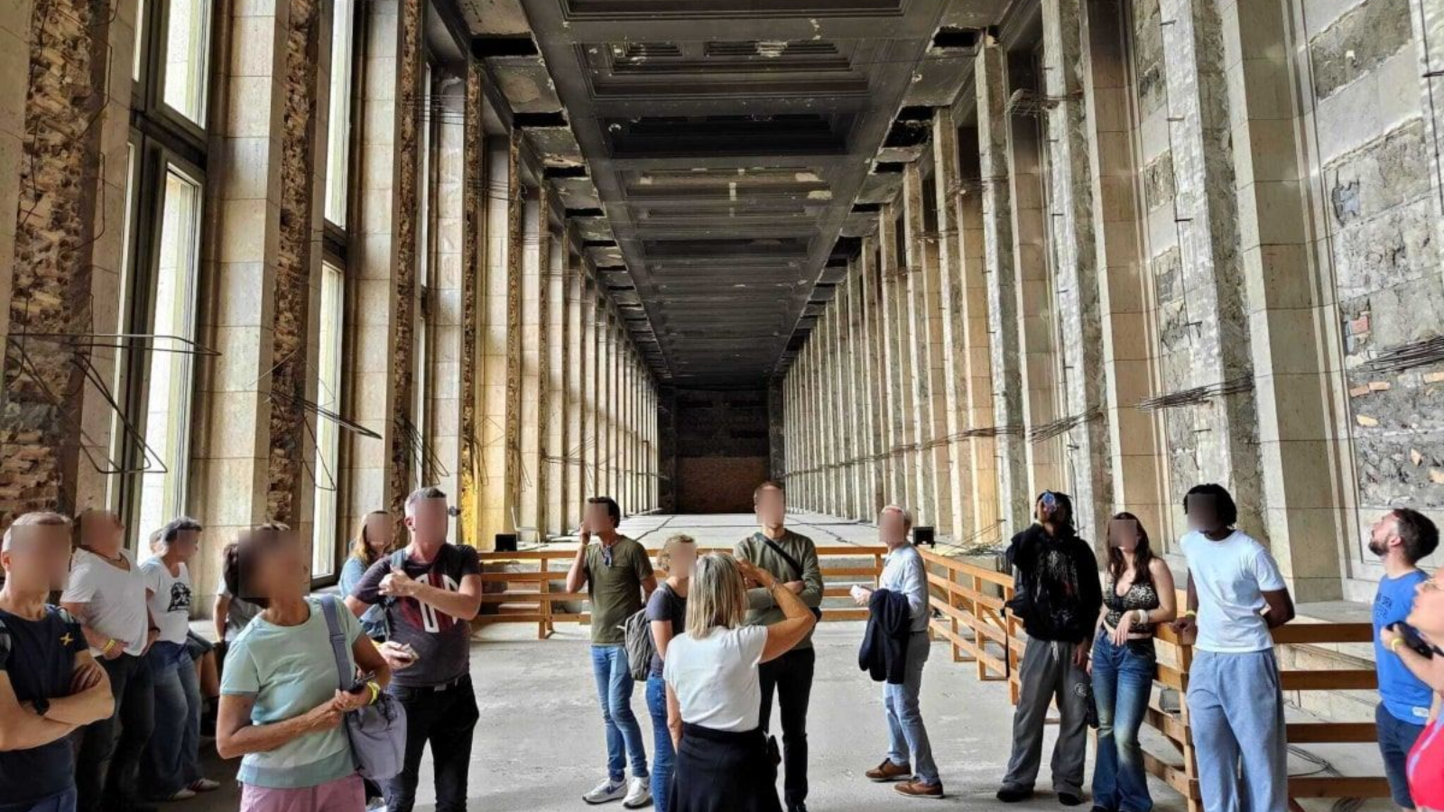 Mythos Tempelhof Large, decaying hall with columns, tour group looking towards the vanishing point.