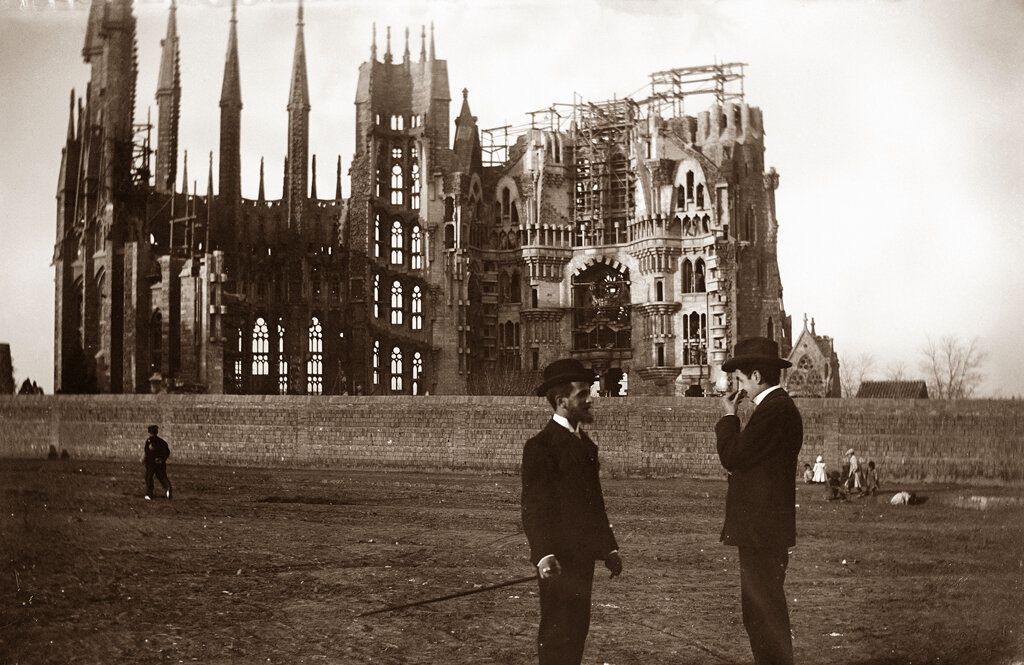 Two men standing in a field with a large building in the background