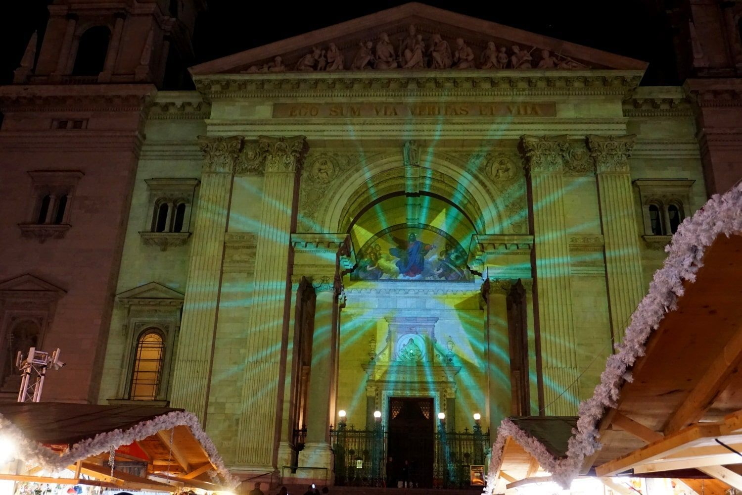 A large building is lit up at night with a projection on the front (Oper Budapest) 