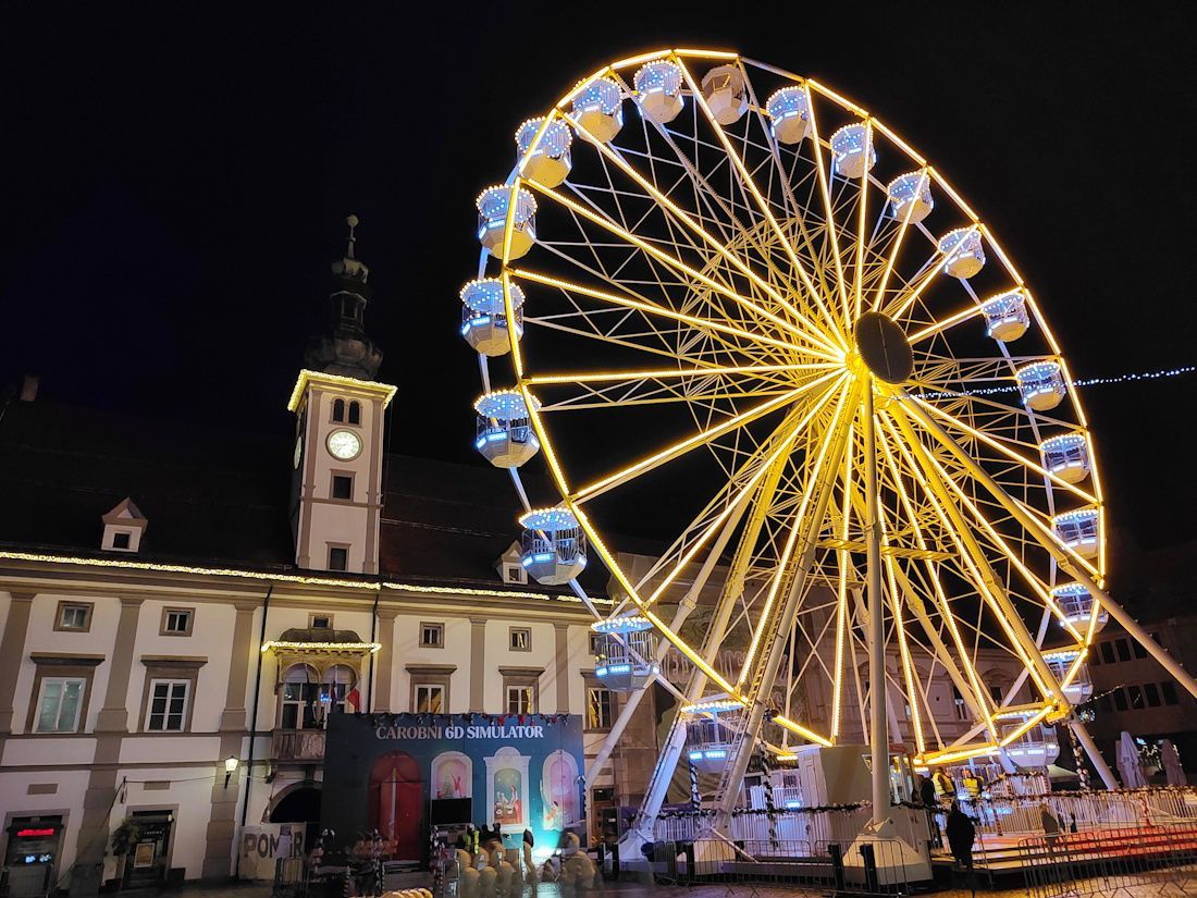 Ferris wheel illuminated at night in front of a historic building.