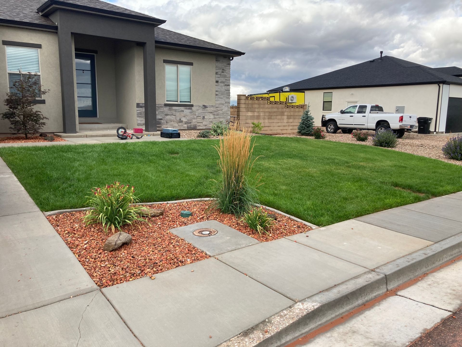 A house with a green lawn and landscaping in front. A white pickup truck is parked in the distance.