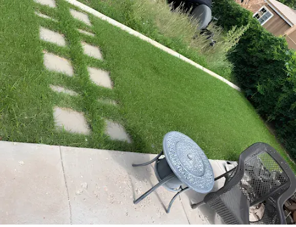 Patio with a table and chair, grass, and stone pathway.